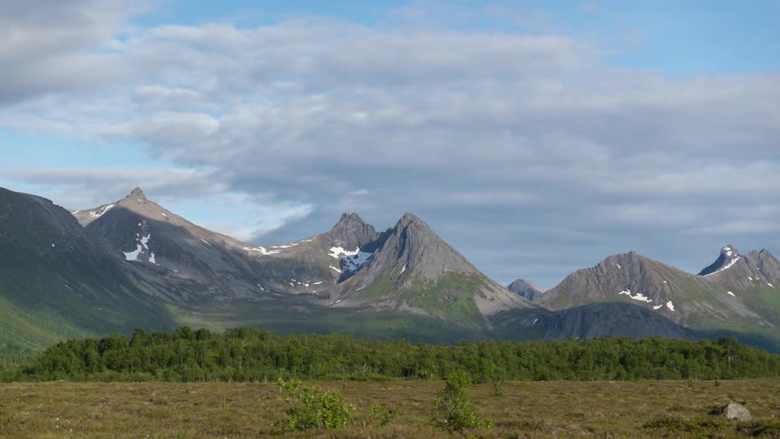 Clouds pass by above valley and mountain peaks