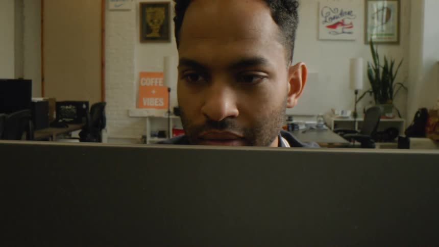 The worker in the office is reading his laptop