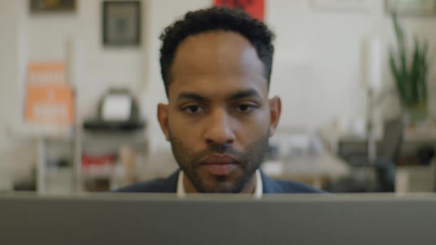 The man is looking over something on his laptop