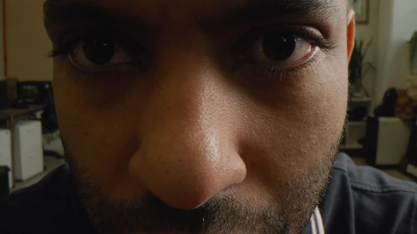 Man working in an office during the daytime rubs his eyes