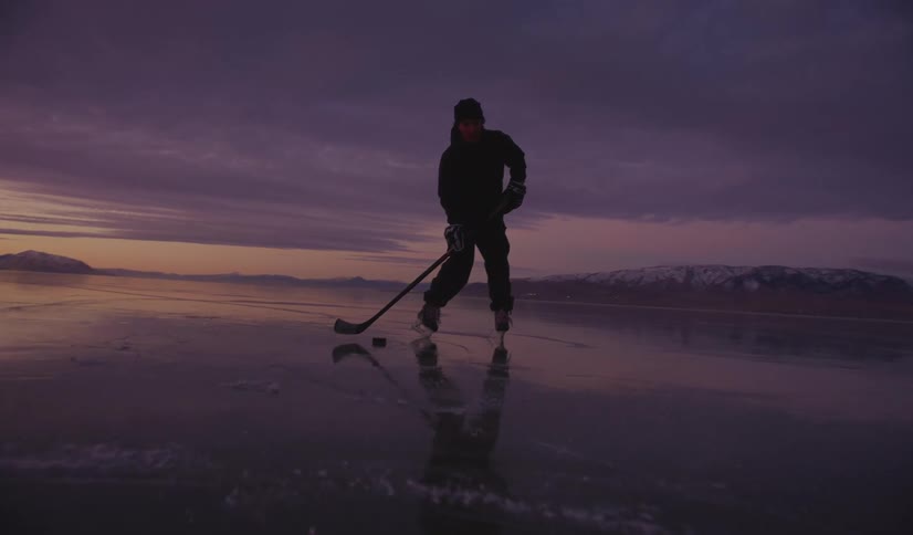The man shoots the hockey puck on the frozen lake