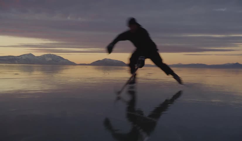 Young man holds his hockey stick moving the puck as he skates across the ice