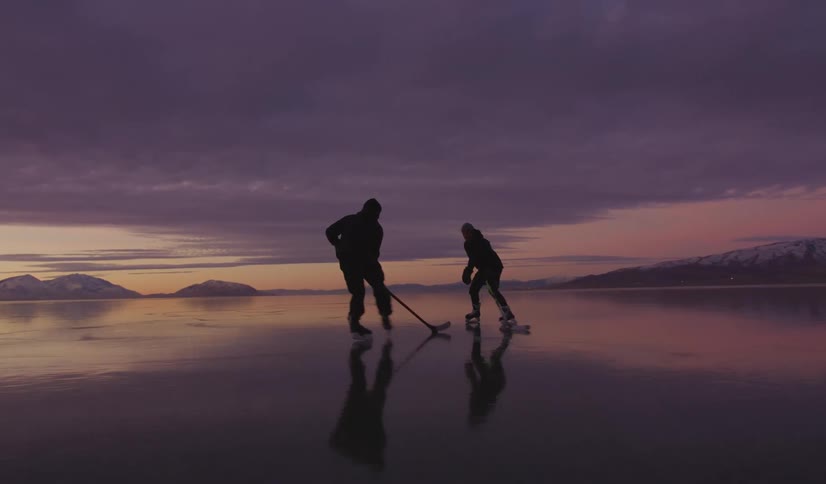 Two people playing hockey outdoors on a frozen lake