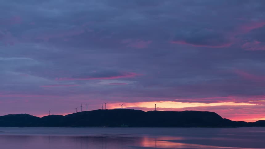 Sunset near some wind turbines and a body of water