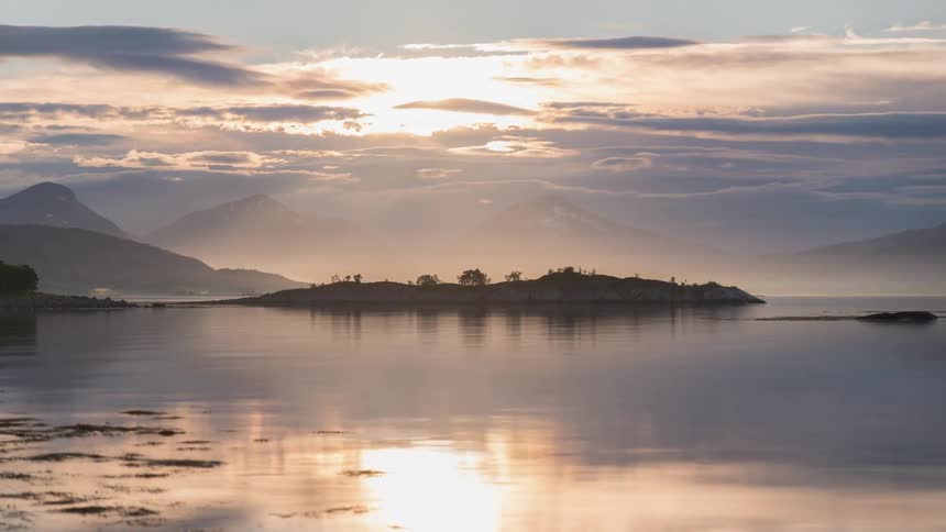 Morning clouds flowing over misty lake and mountains
