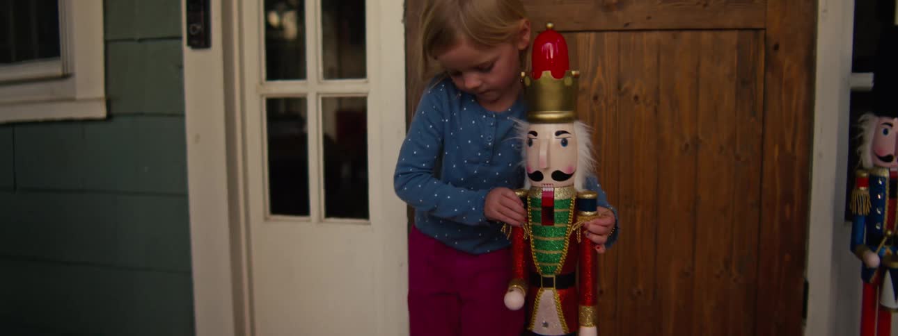 Little girl stands outside her front door with a nutcracker soldier decoration