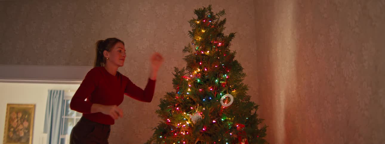 A woman decorating a christmas tree in a room