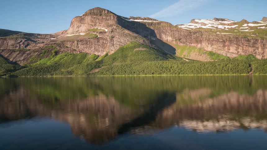 The water is calm before this mountain at sunrise