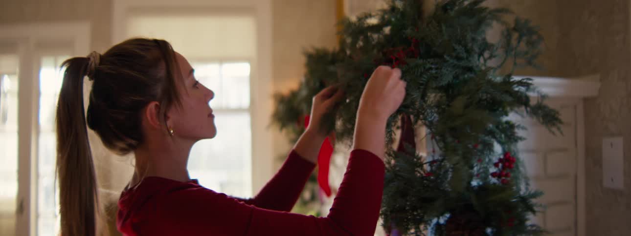 Woman places ornament on christmas tree
