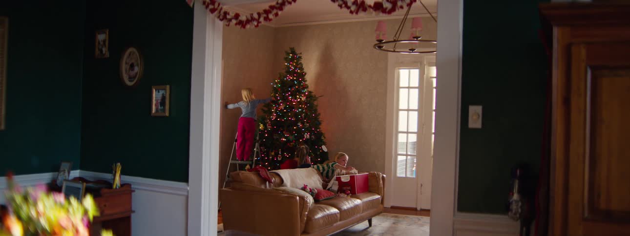 Adult woman and two young girls decorating a christmas tree on a living room indoors during day time