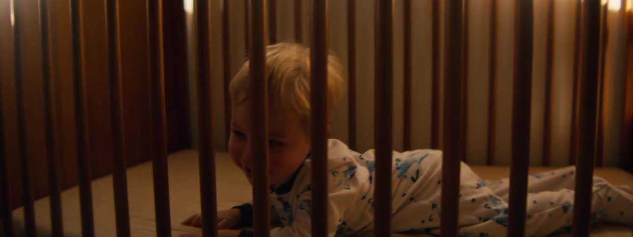 Little boy rolling and playing in a crib