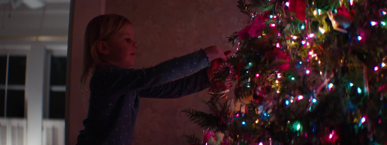 Little girl putting decorations on the christmas tree