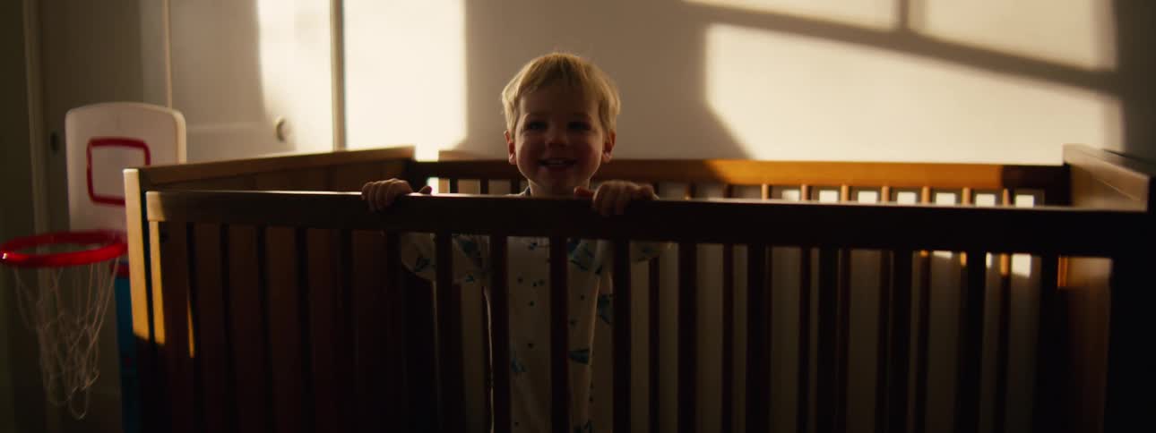 Toddler standing in his crib in his bedroom