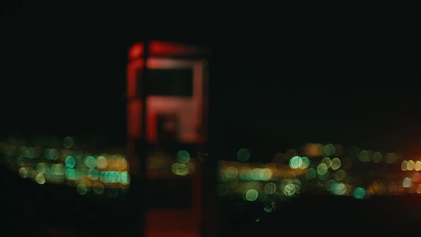 Car drives past a booth while the city lights shine brightly at night
