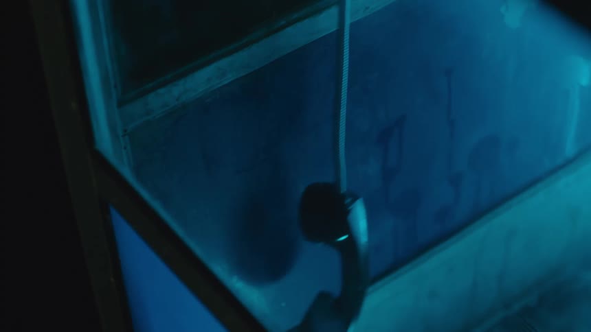Telephone hanging by a cord inside a bluelit booth