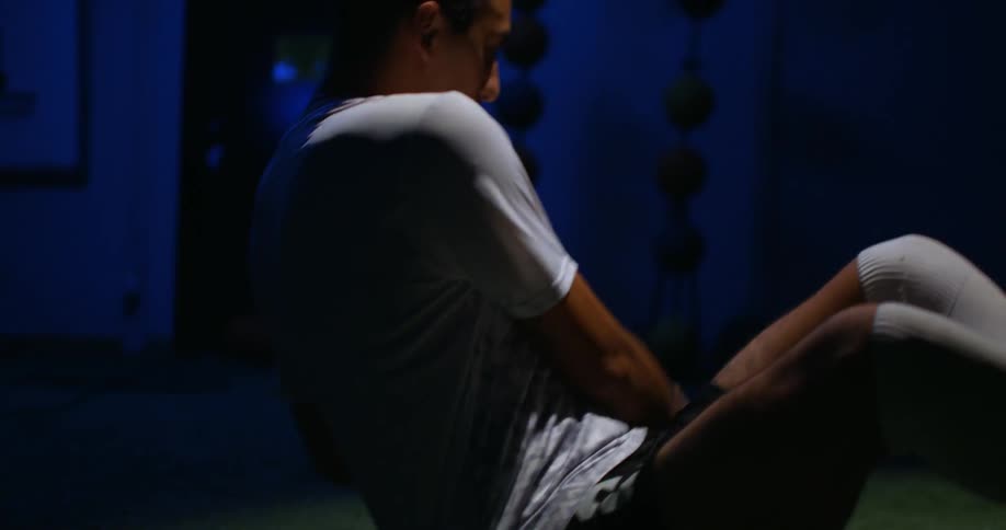A man sits on the ground dribbling a basketball