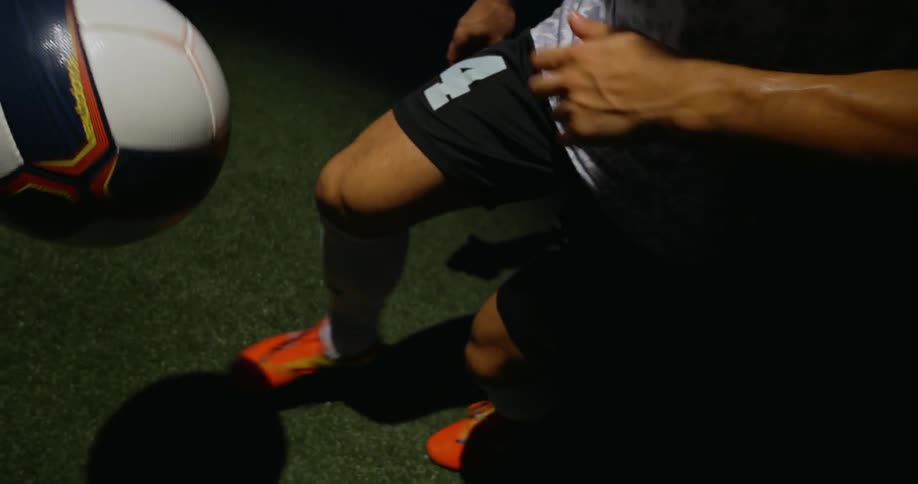 A soccer play kicks and balances a soccer ball