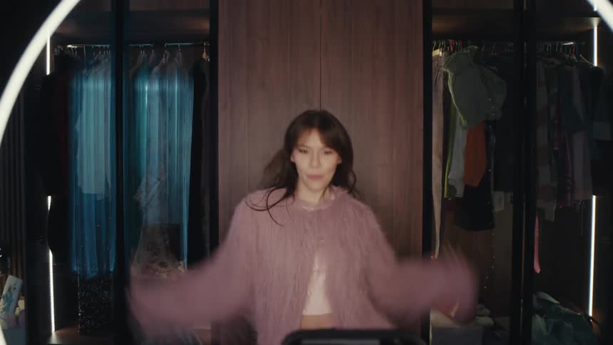 A woman dances indoors in front of her smartphone and ring light