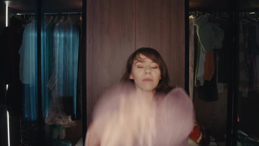Woman records herself using a smartphone and a ring light while dancing in her bedroom
