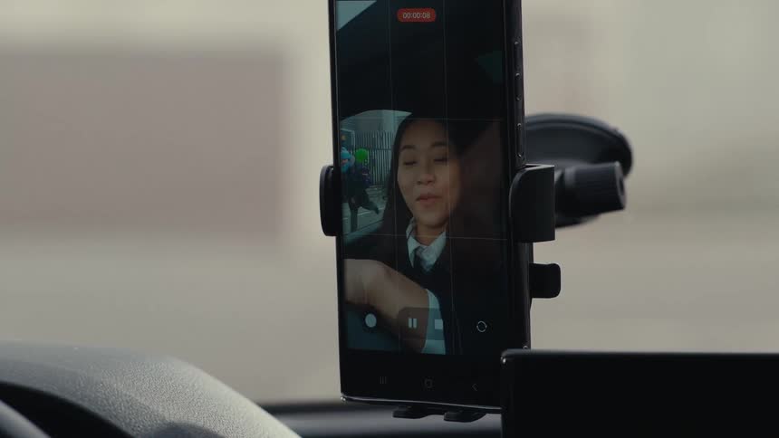 Cheerful woman recording herself inside a car