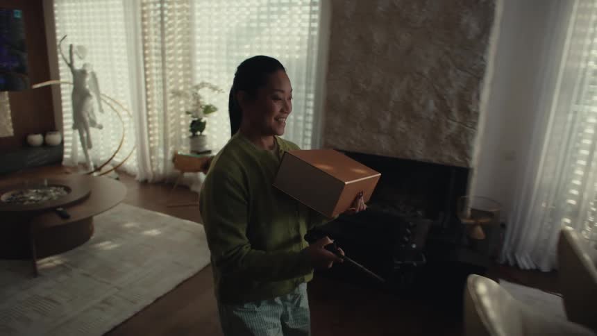 Woman performs a product unboxing in front of a phone on a tripod with indoor lighting