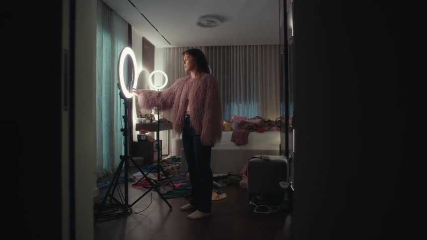 Woman dances in a bedroom with ring lights and recording equipment