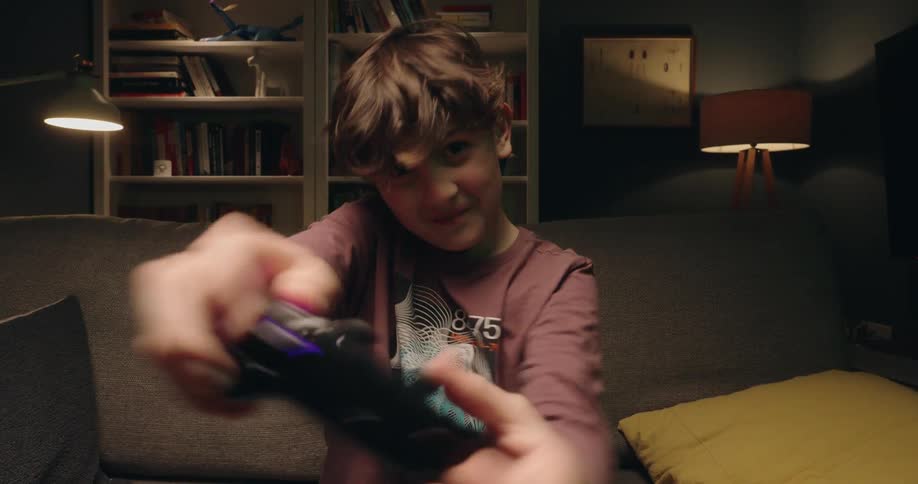 A young boy celebrates after rapidly pressing buttons on his video game controller