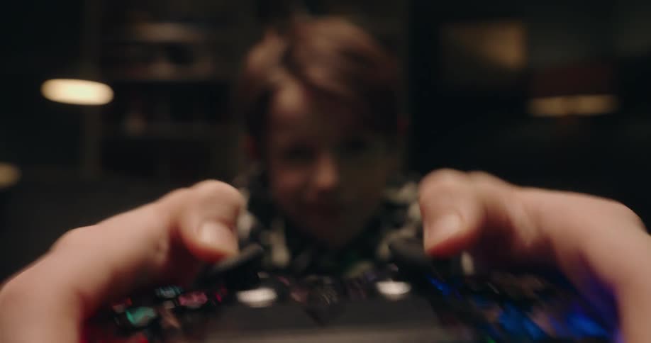 Boy holding his arms out moving the controls on a video game controller playing a game