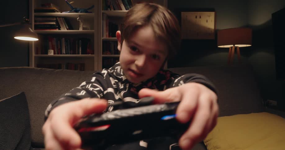 A young boy actively and joyfully engages in a video game while holding a controller in a cozy living room