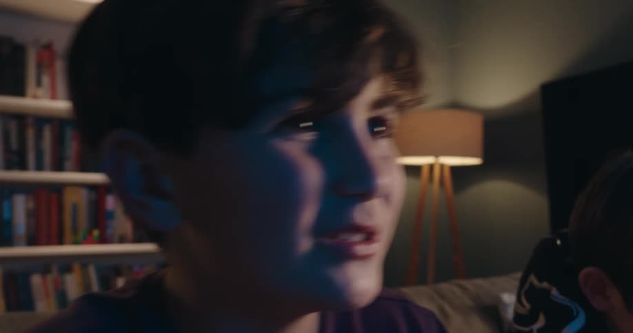 Boys sitting on a couch playing video games in a living room