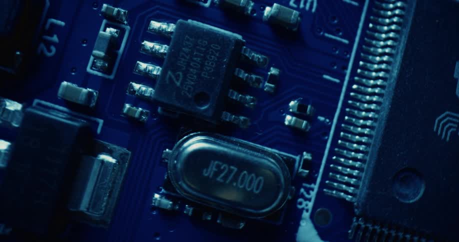 Closeup of internal circuitry with microchips and a crystal oscillator on a deep blue substrate