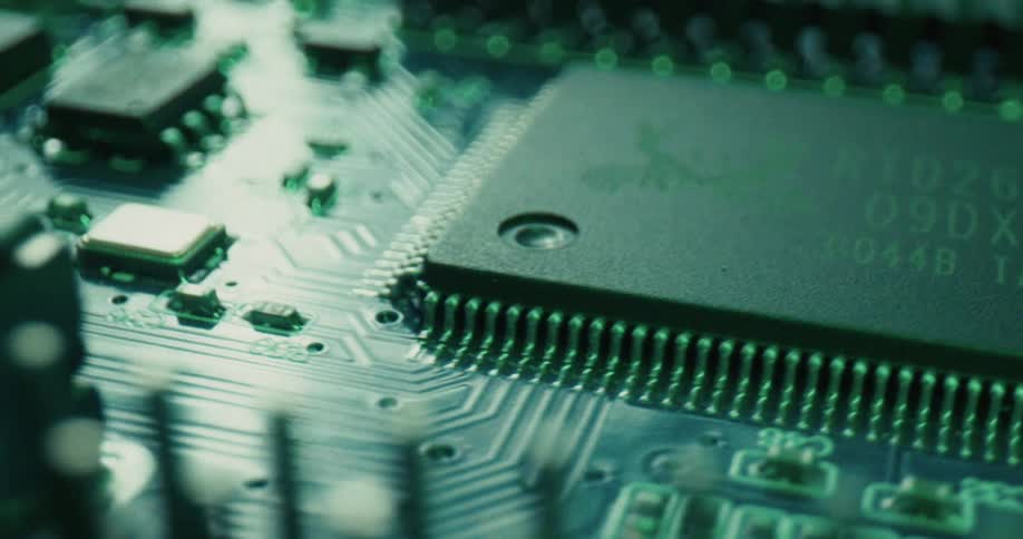 A detailed circuit board highlighting a central microchip and surrounding components as the scene shifts through vibrant blue purple and orange lighting to reveal the intricate textures of the hardware