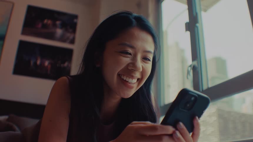 A woman smiles while having a video call via her smartphone