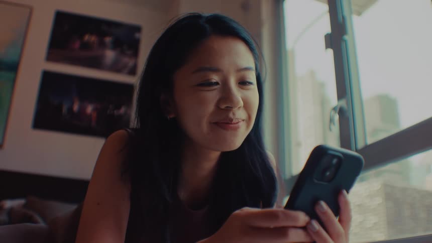 A woman smiles while having a video call via her smartphone