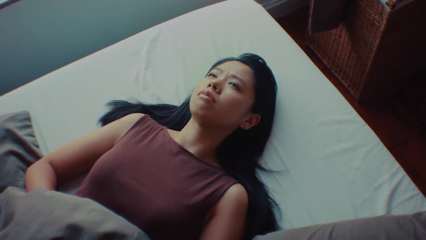 Woman lying on a bed looks upward while remaining awake