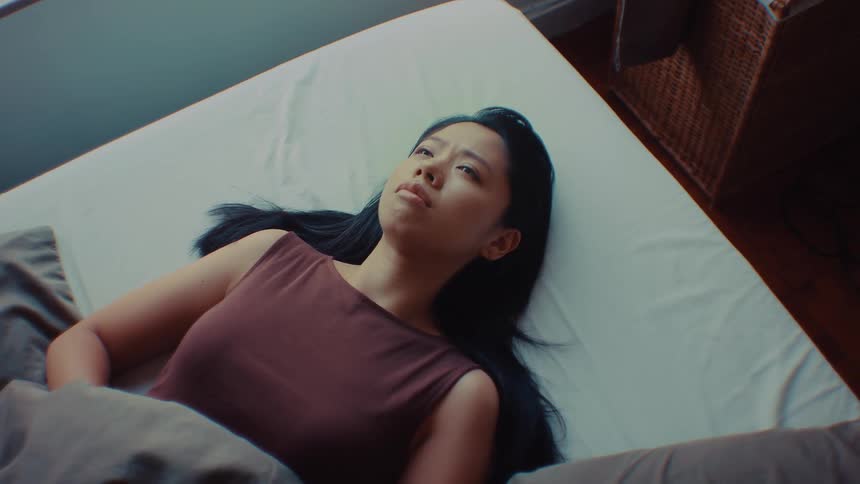 Woman lying on a bed looks upward while remaining awake