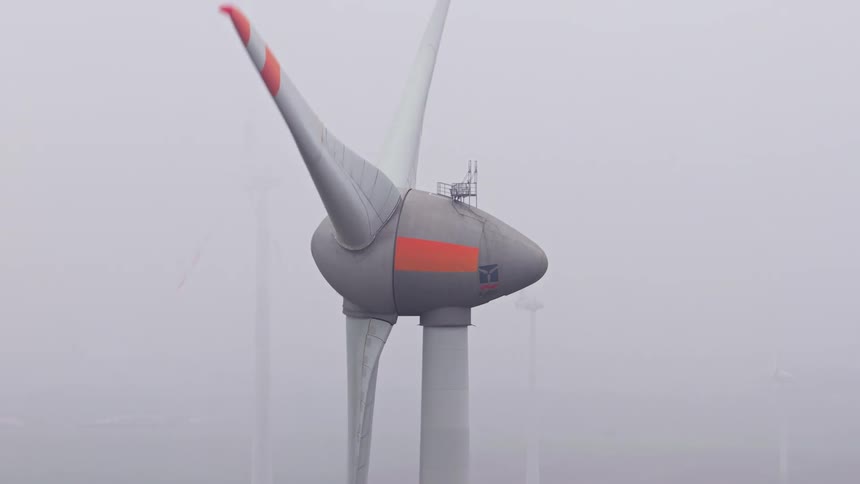 Wind turbine with partially visible blades in a lowvisibility environment caused by fog