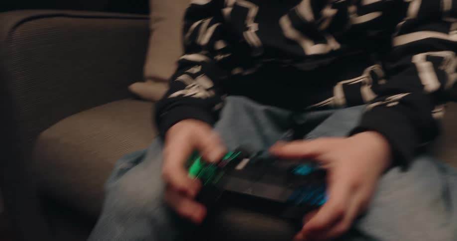 Two kids play a video game together while sitting on the couch in the living room