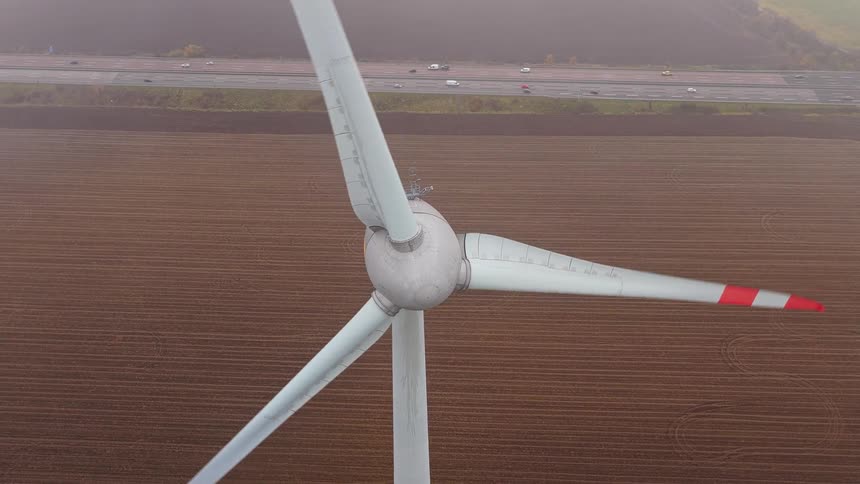Topdown view of a wind turbine over farmland with a highway in the background