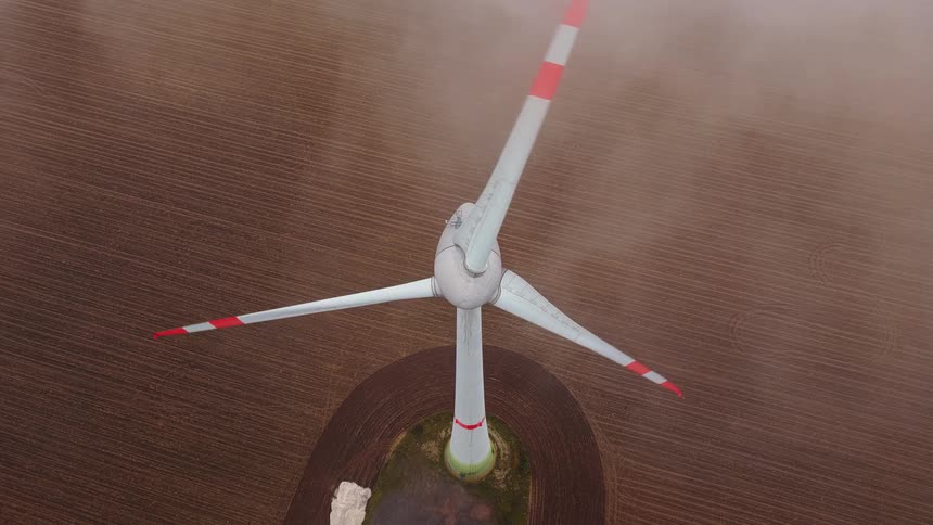 Wind turbine turns slowly as low lying clouds pass by