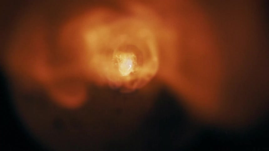 Incandescent blast amid particles and smoke in dark setting