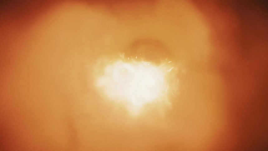 A bright flame casts a warm abstract glow burning inside a circular tunnel