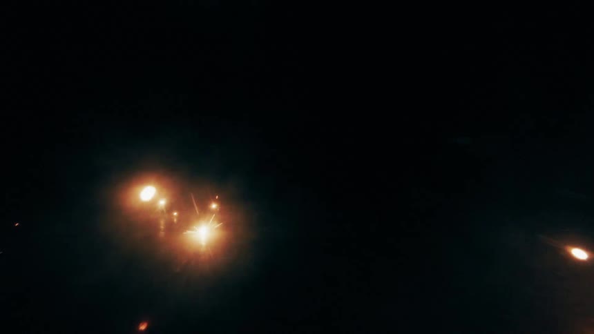 Fireworks emitting bright sparks at night with reflections on the ground