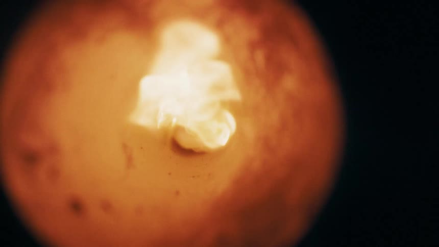 Fire through a circular opening with textured edges in a dark environment