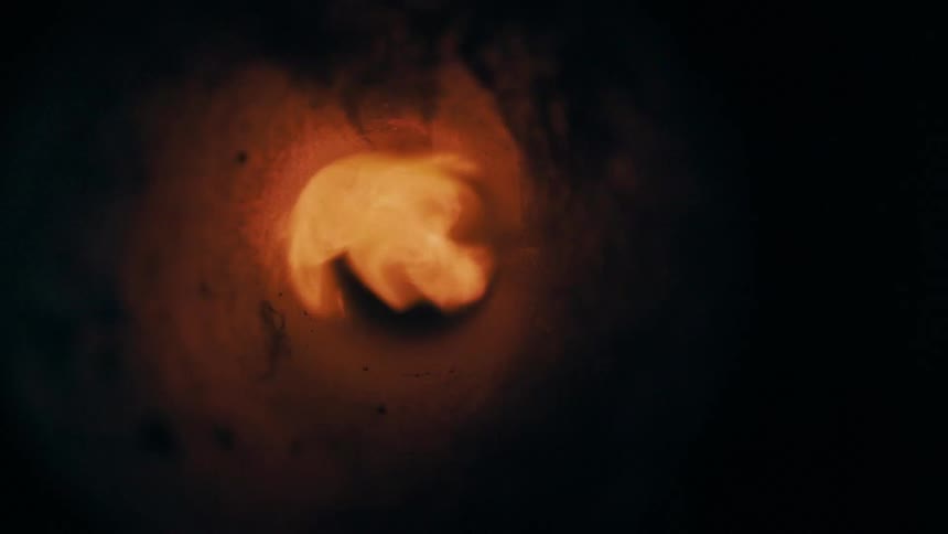 A bright flame burns at the center creating an intense abstract effect inside a dark tunnel