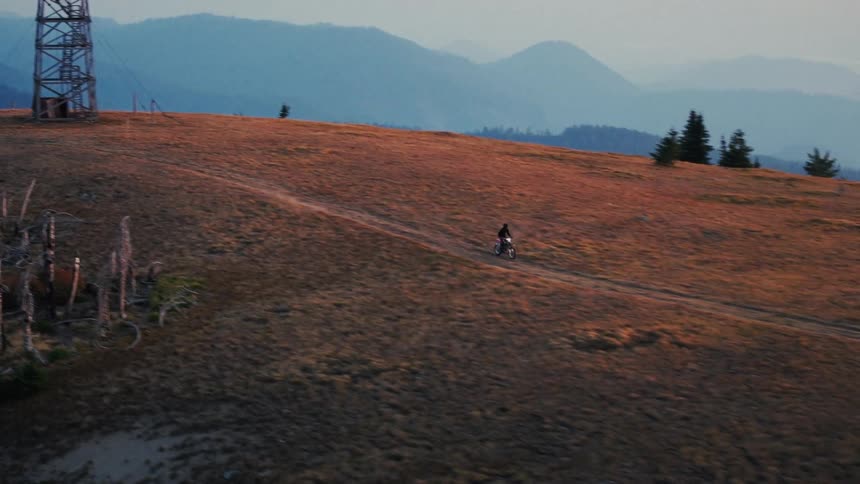 The man races down the hill on his dirt bike