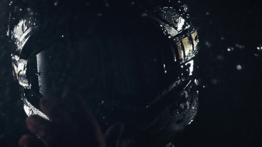 Person wearing a motorcycle at night during a rainstorm reaches a hand up