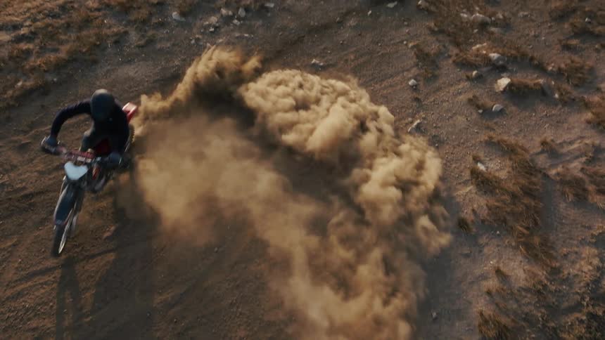The dirt bike spins and creates a dust cloud