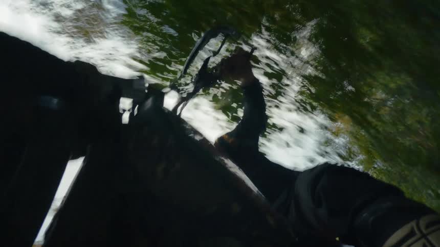 A close up of a person on a motorcycle riding with several trees and the sky around
