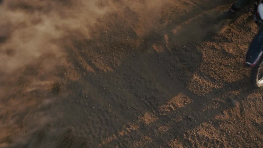 Motocross rider skidding on dirt terrain with a large cloud of dust